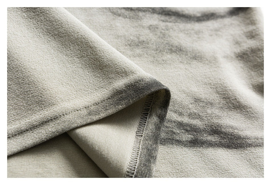 Close-up of an ivory-gray mottled shirt hem, showing the folded edge and overlock stitching.