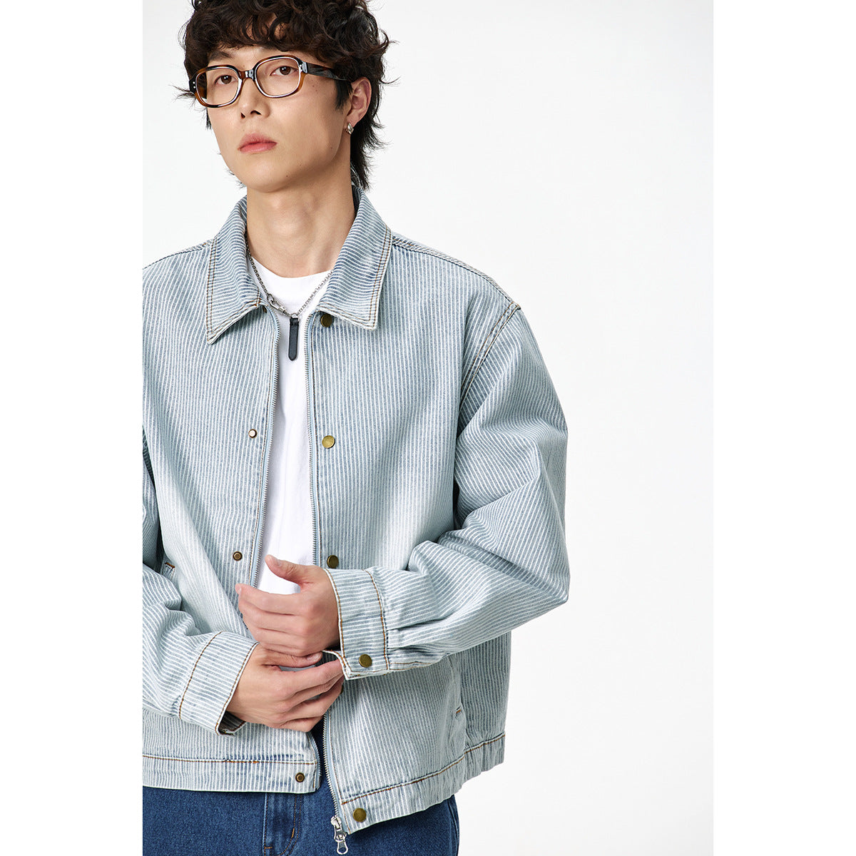 Close view of a model wearing a light blue-and-white striped jacket with a pointed collar, brass snaps and zip front.