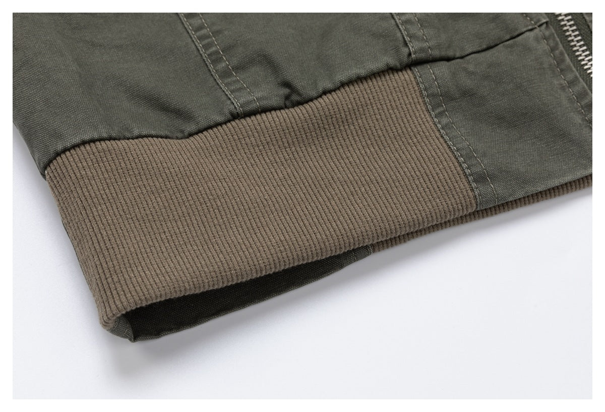 Close-up of the jacket's wide brown ribbed hem band and olive-gray fabric.
