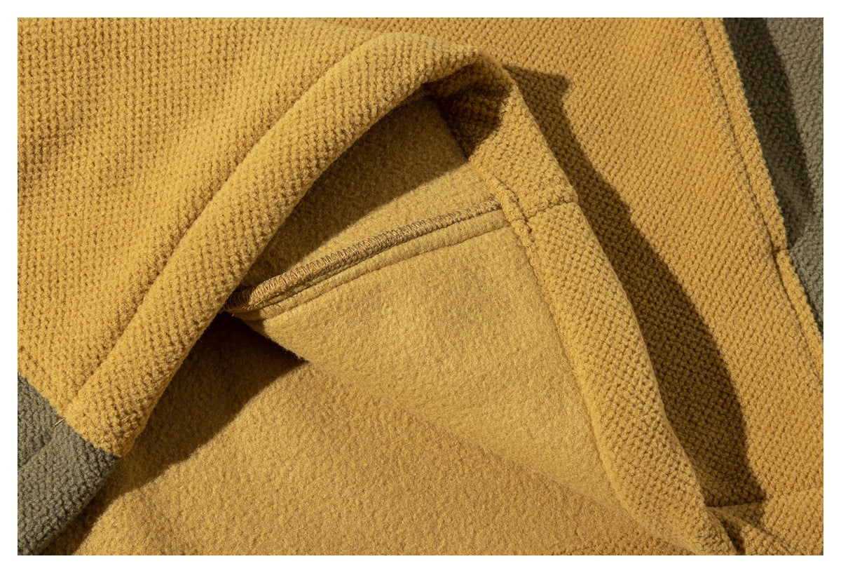 Close-up of mustard-yellow textured fabric with folded edges and visible stitching.