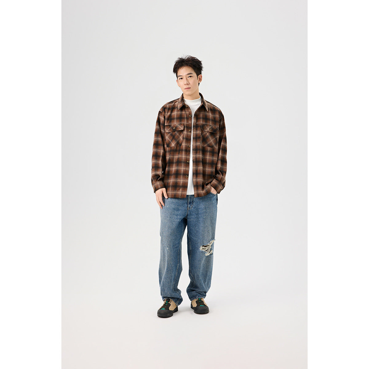 Model wearing a brown plaid button-up overshirt with flap chest pockets, a white top, and distressed blue jeans.