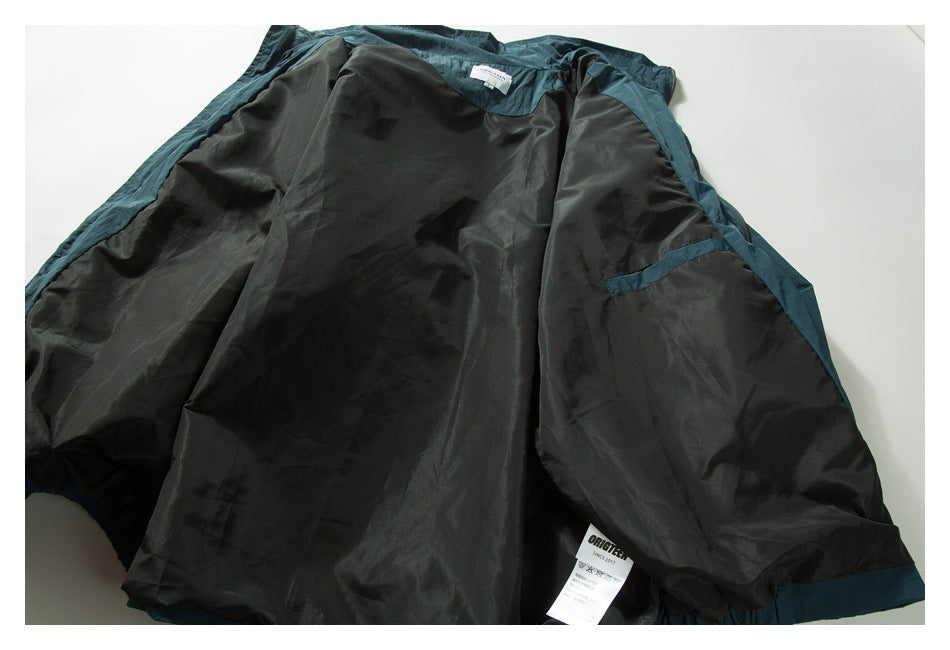 Dark teal jacket laid open to show its black lining, seams, and interior labels.