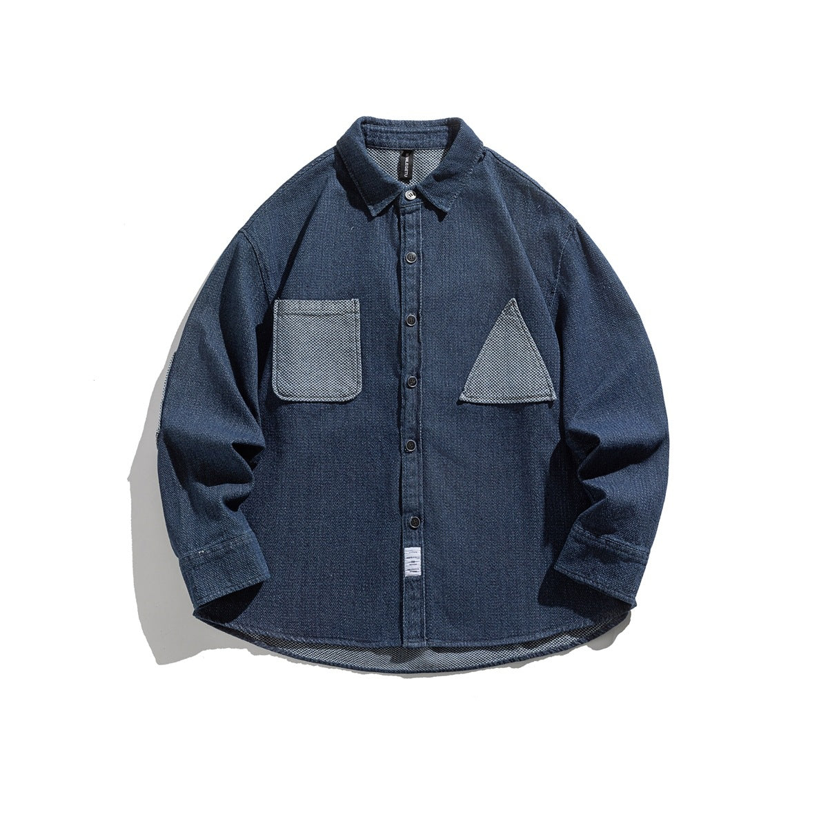 Washed blue long-sleeve button-up shirt flat lay with contrast rectangular and triangular patch pockets
