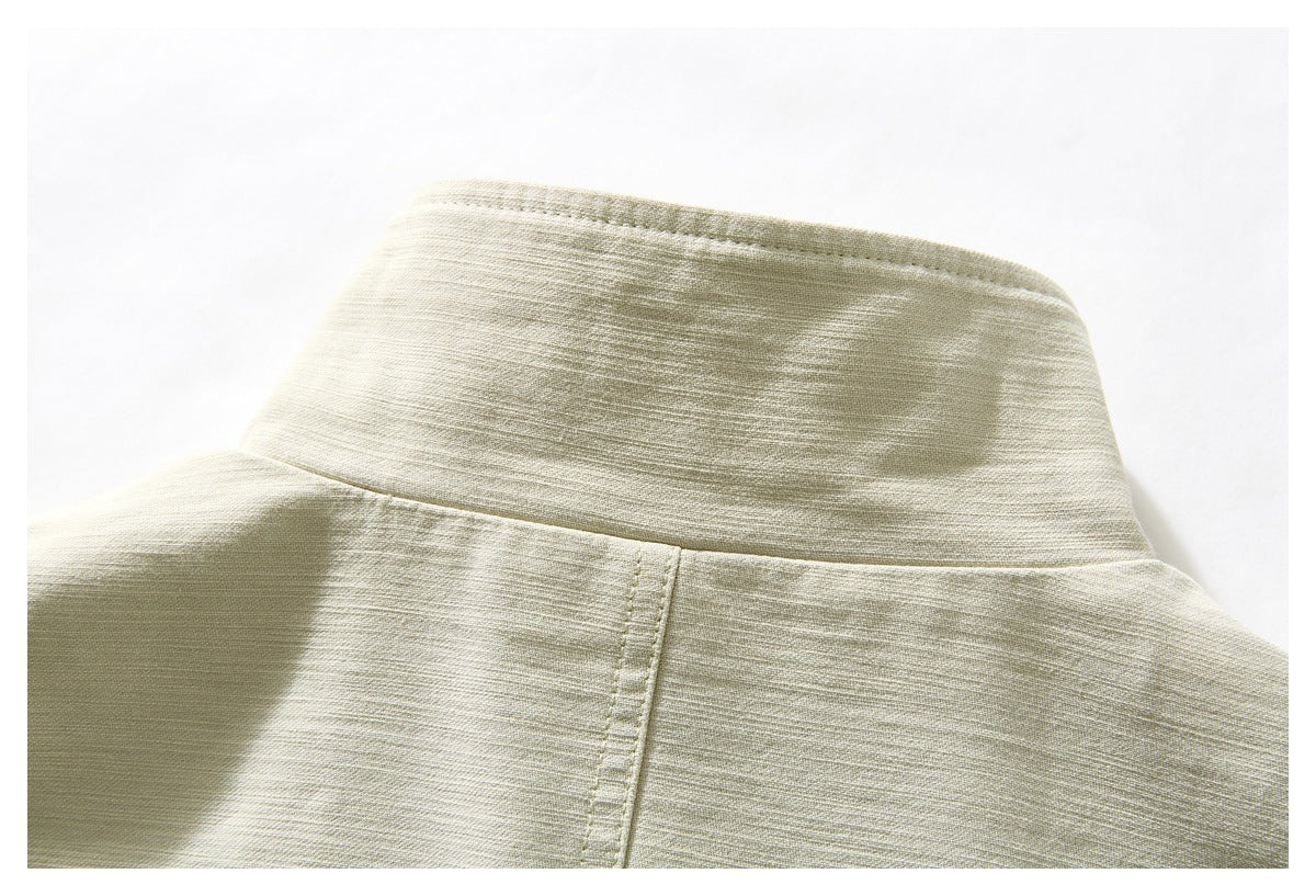 Close-up of the pale beige jacket's upright collar and upper back seam.