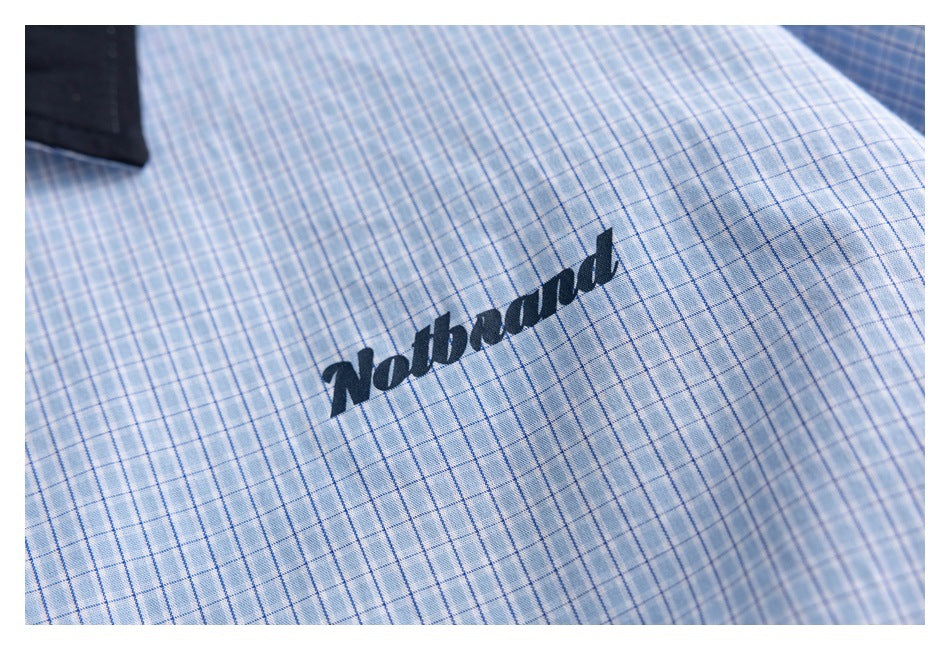 Close-up of dark script lettering on light blue plaid fabric.