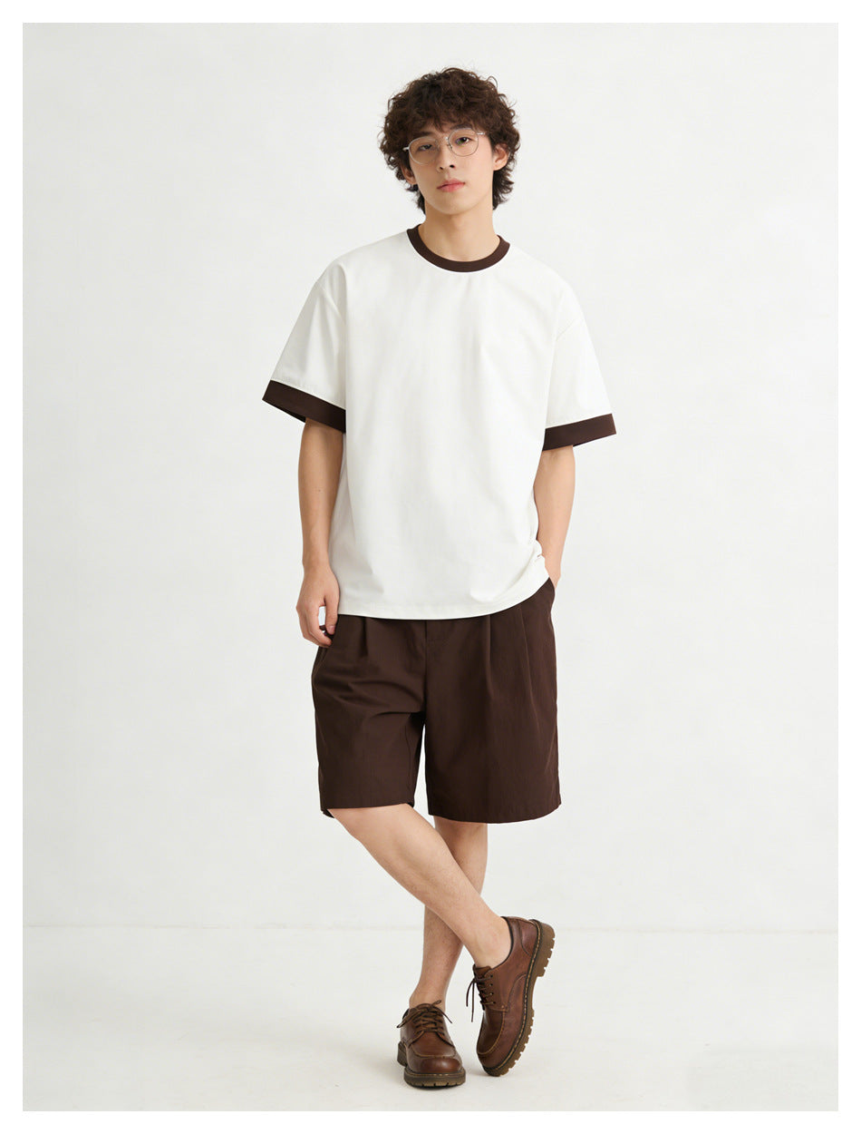 Front view of a model wearing a white T-shirt with dark brown collar and sleeve cuffs, paired with dark brown shorts.