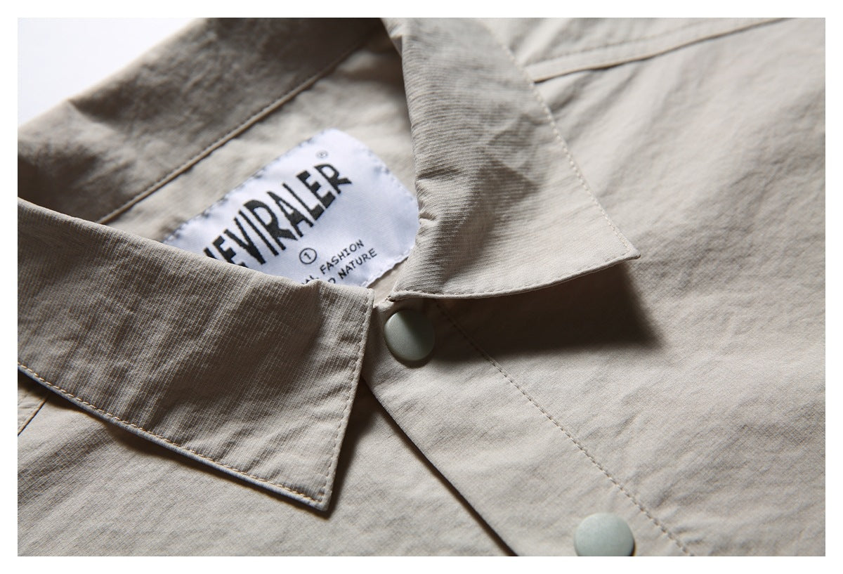 Close-up of a light beige shirt collar, pale snap buttons, and a sewn-in brand label.