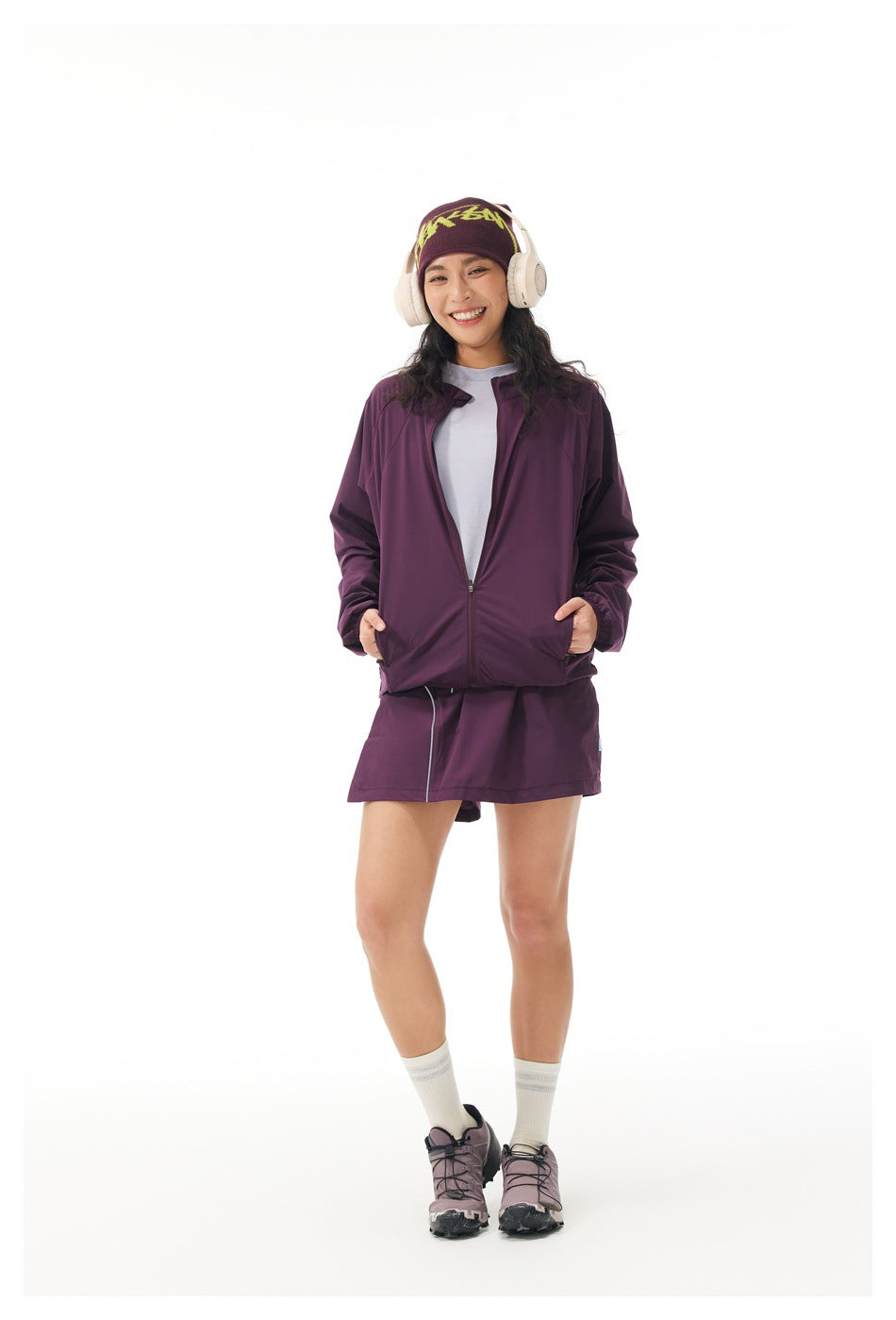 Model wearing a plum zip-front jacket and matching short skirt over a light shirt.