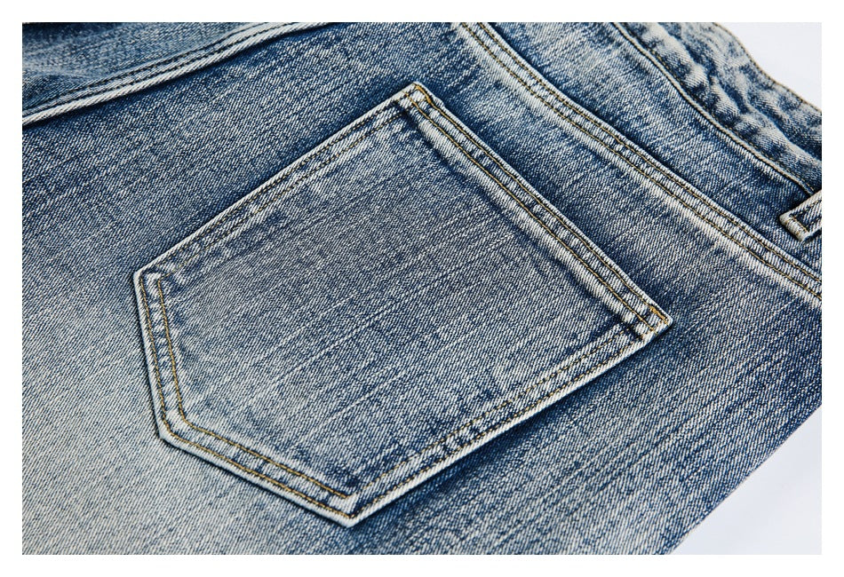 Close-up of a rear pocket on faded blue denim jeans with visible contrast stitching.