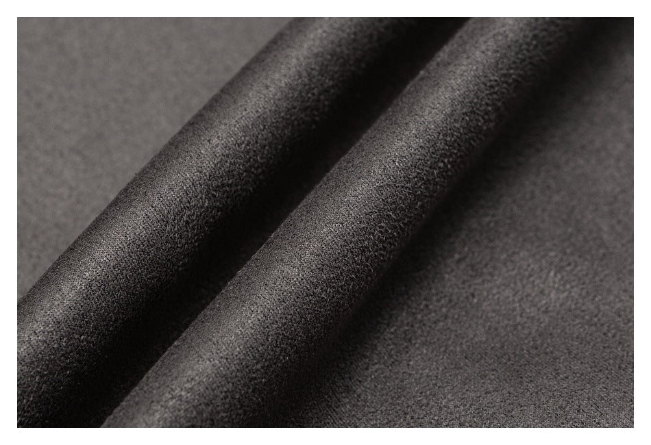 Close-up of dark charcoal fabric folded into soft diagonal ridges, showing its fine textured surface.