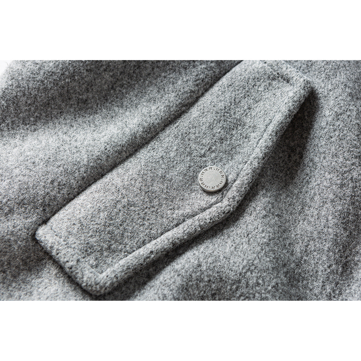 Close-up of a gray jacket pocket flap and round metal button.