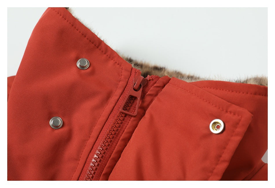 Close-up of a rust-red coat front zipper, metal snaps, and brown faux-fur lining.