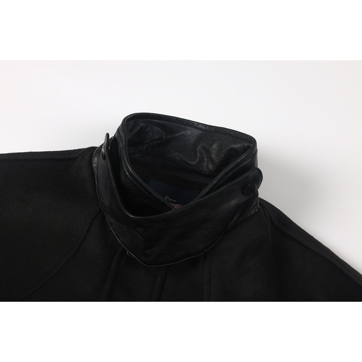 Close-up of a black jacket's high collar, showing a leather-look collar and interior label.