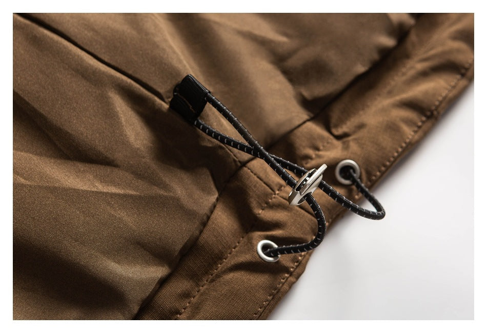 Close-up of a black adjustable drawcord and metal eyelets at the edge of a brown jacket.