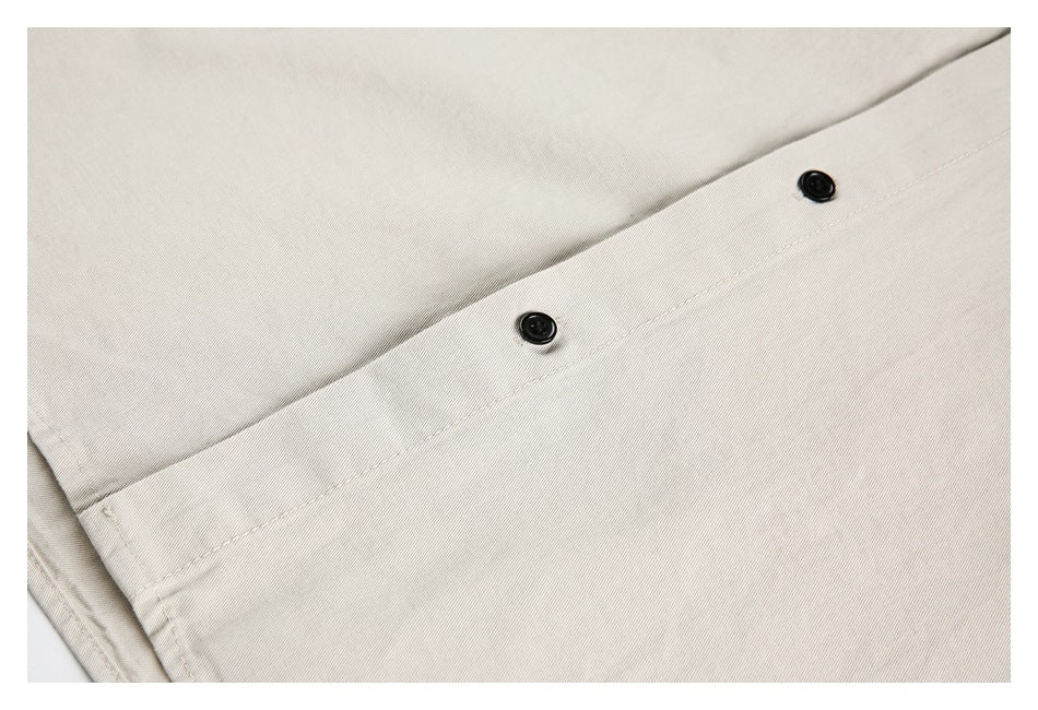 Close-up of two black buttons and a stitched placket on light beige fabric.