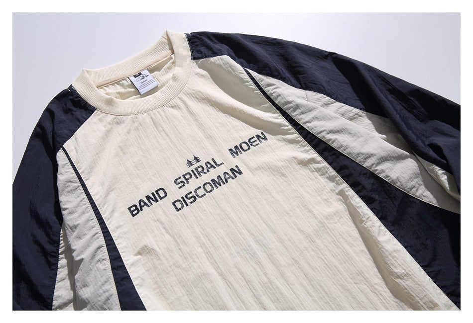 Close-up of the pullover's ivory ribbed neckline, navy sleeve panels, and black lettering across the chest.