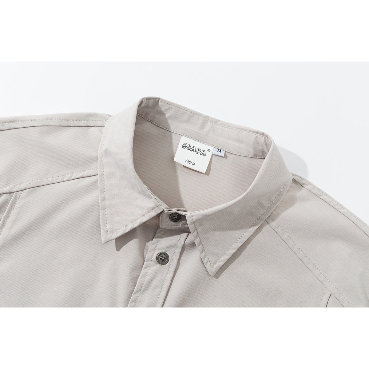 Close-up of a light beige short-sleeve shirt collar, top buttons, and inner neck label.