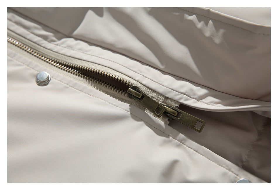 Close-up of a light beige jacket front with a metal zipper and snap fastener.