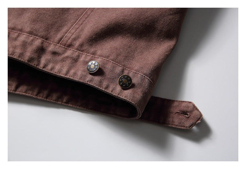 Close-up of a brown jacket cuff strap with two metal buttons and visible stitching.