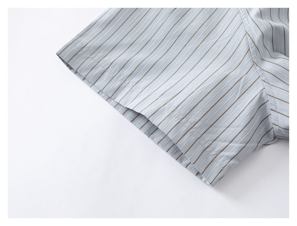 Close-up of a short sleeve and stitched cuff on a pale blue-gray shirt with thin vertical stripes.