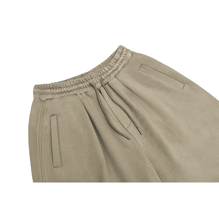 Close front view of taupe wide-leg pants with an elastic drawstring waist and slanted pockets.