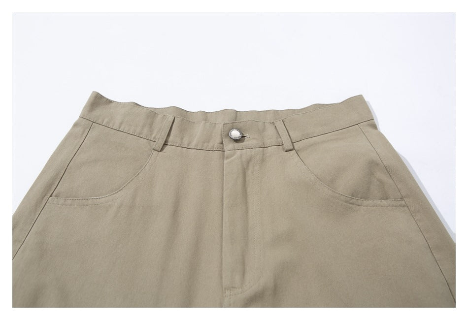 Front close-up of beige trousers showing the waistband, button, belt loops, and curved pockets.