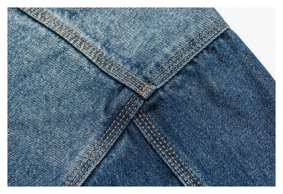 Close-up of intersecting blue denim panels with multiple rows of tan stitching.