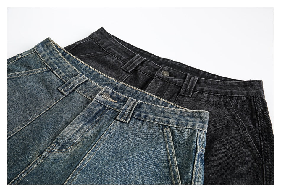 Close-up of blue and black denim shorts showing waistbands, belt loops, buttons and front pocket seams.