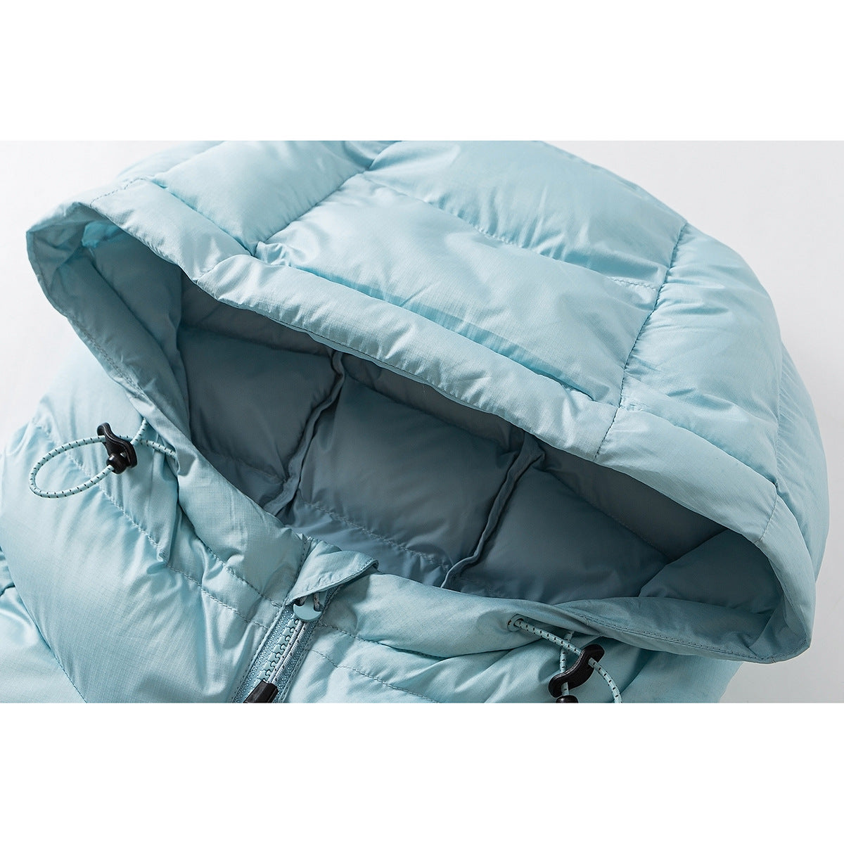 Close-up of a light blue quilted puffer jacket hood, drawcords, and upper zipper.