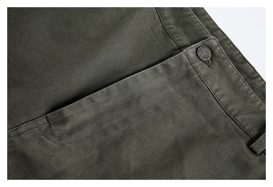 Close-up of olive-gray trousers showing a slanted pocket seam and engraved waistband button.
