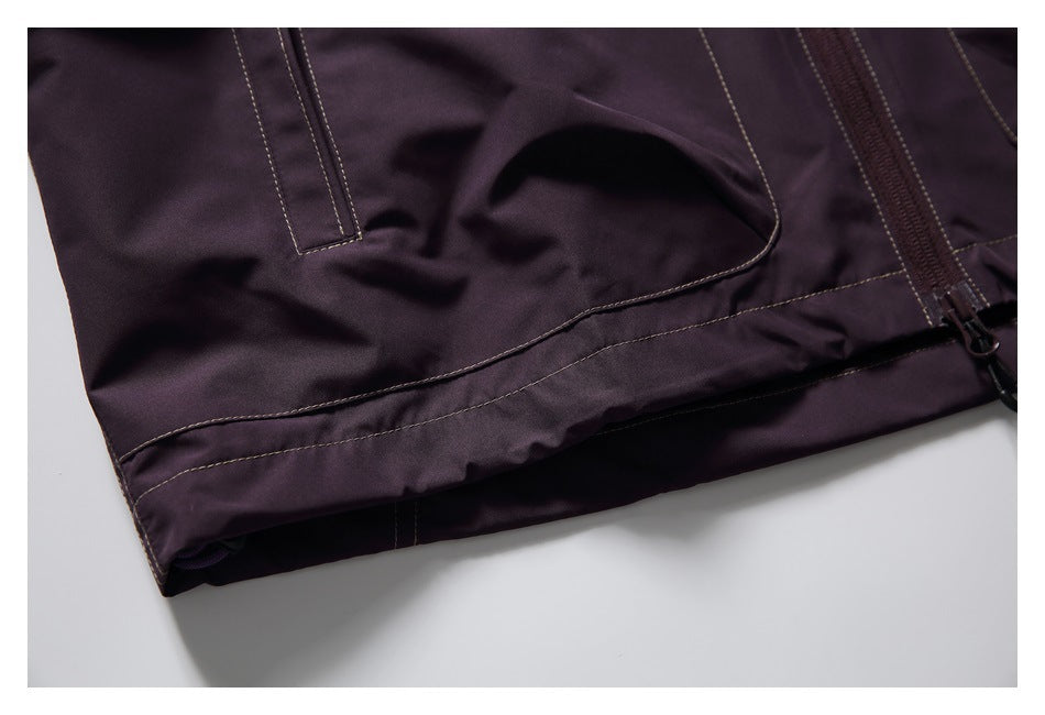 Close-up of dark plum garment with contrast stitching, a curved panel seam and zipper.