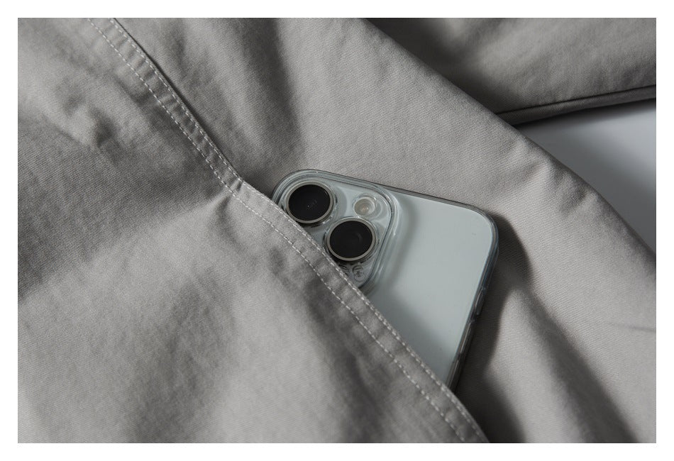 Close-up of a light gray garment pocket with a smartphone partly tucked inside.