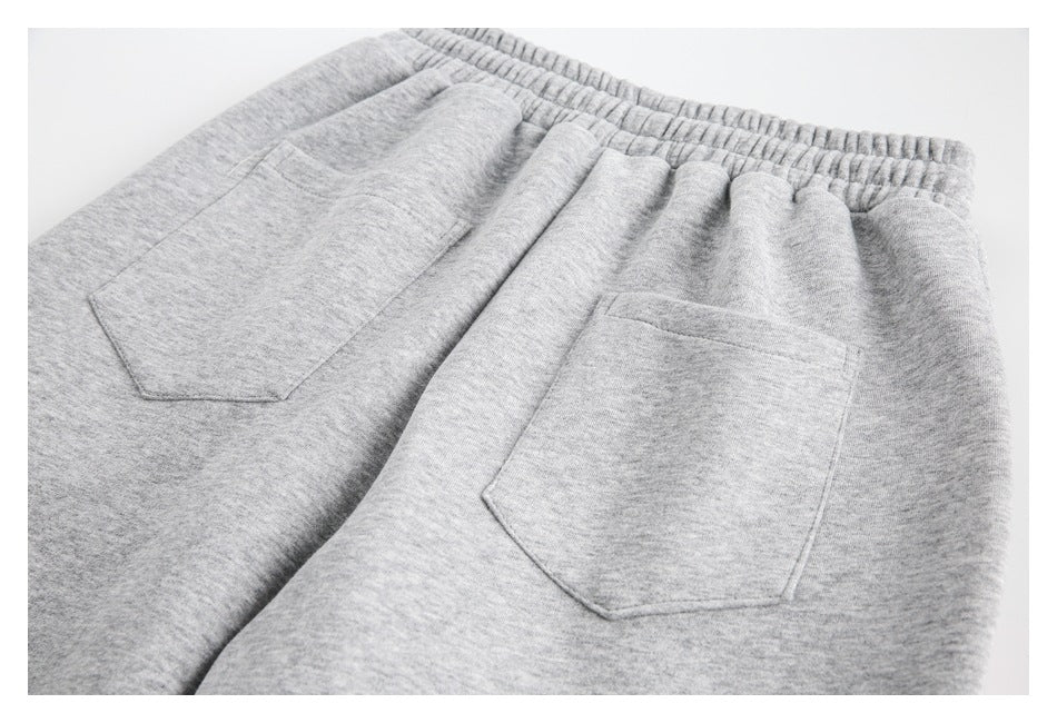 Angled partial back view of light gray heather sweatpants with an elastic waist and two patch pockets.