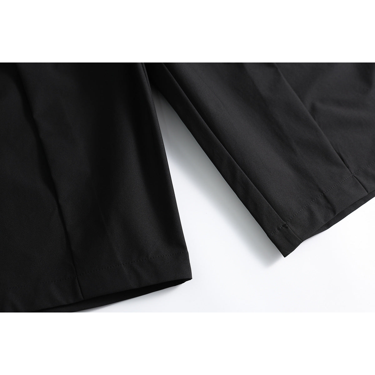 Close-up of black shorts showing the wide leg hems and stitching.