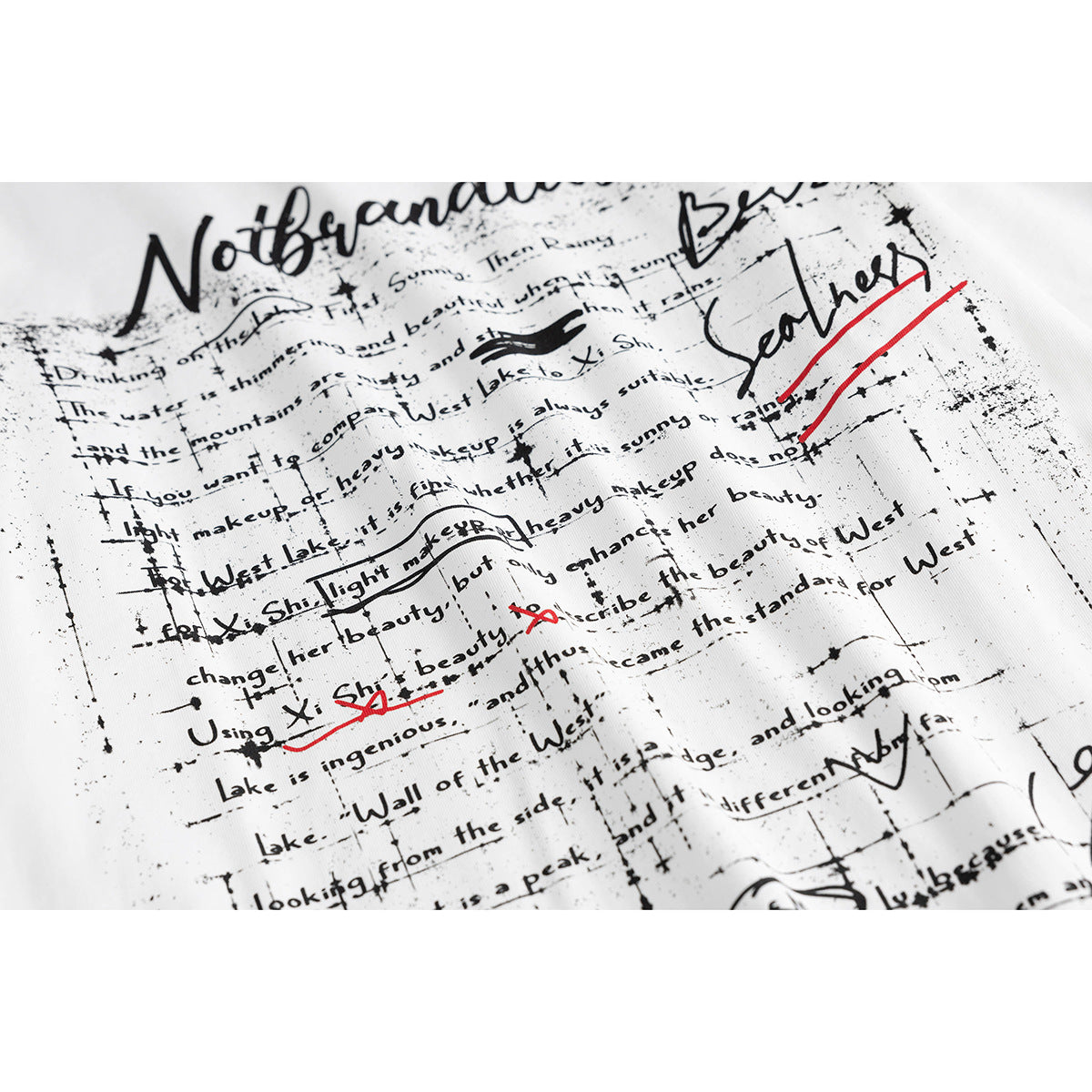 Close-up of a white shirt printed with dense distressed black text and handwritten marks, with red accents.