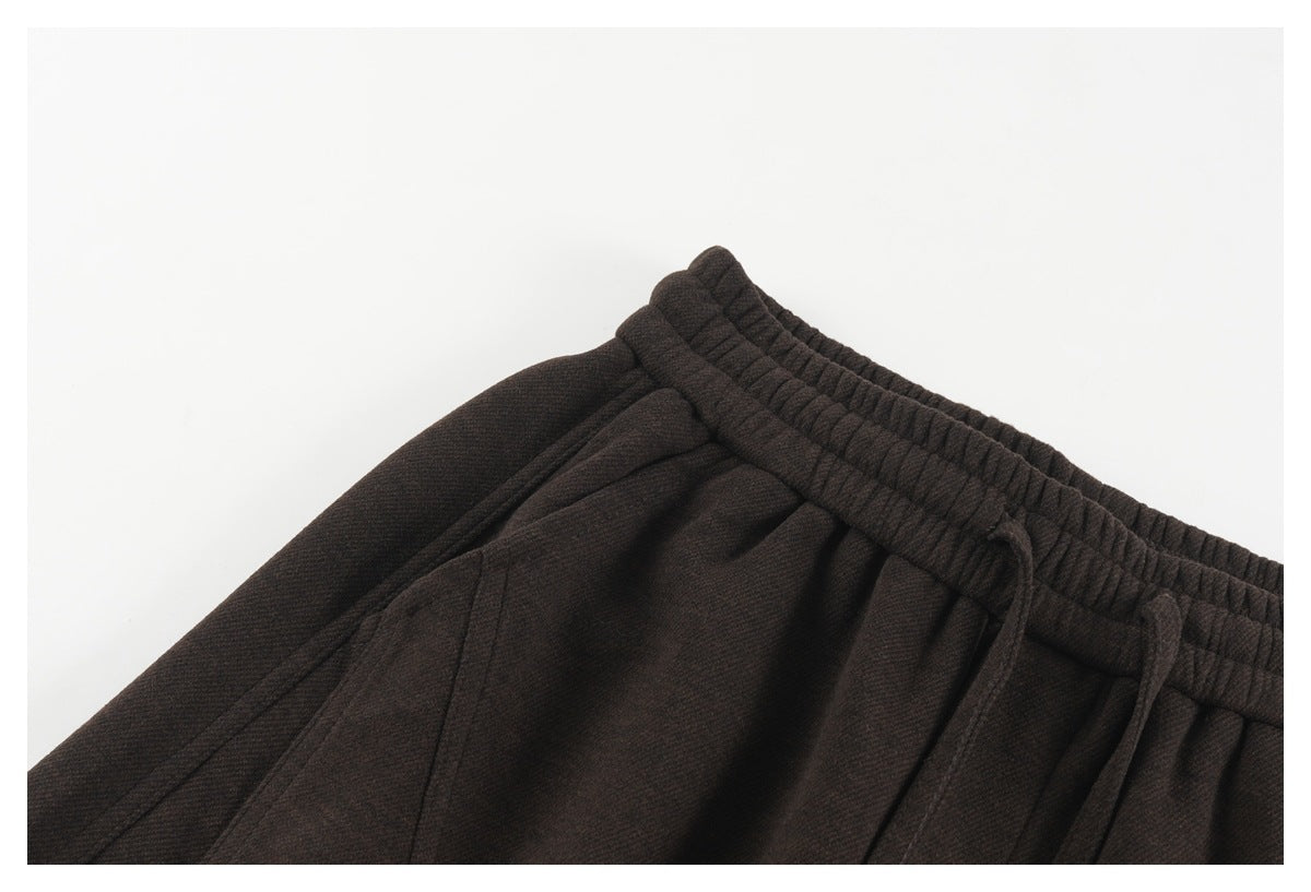 Close-up of dark brown pants showing the elastic waistband, drawstring, and side pocket opening.