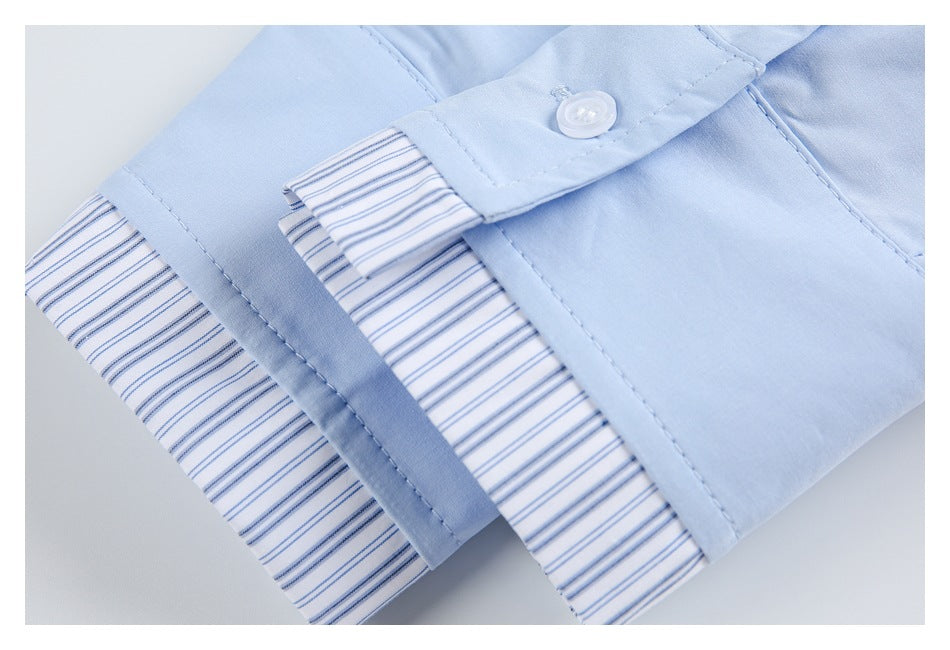 Close-up of a pale blue shirt cuff with a white button and blue-striped inner trim.