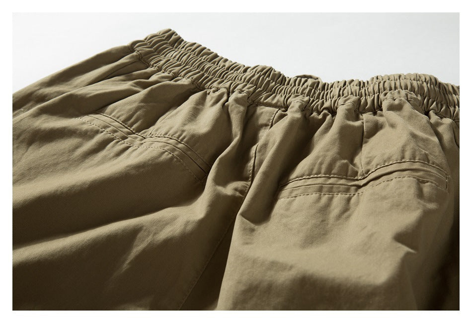Close-up of the gathered back waistband and stitched pocket details on khaki trousers.