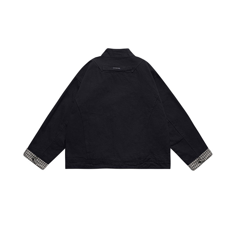 Back view of a black jacket with a small upper-back tag and plaid cuffs.