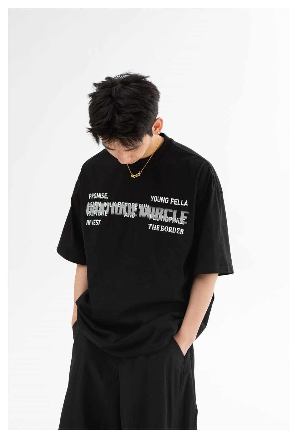 Model wearing a black oversized T-shirt with layered white text across the chest.