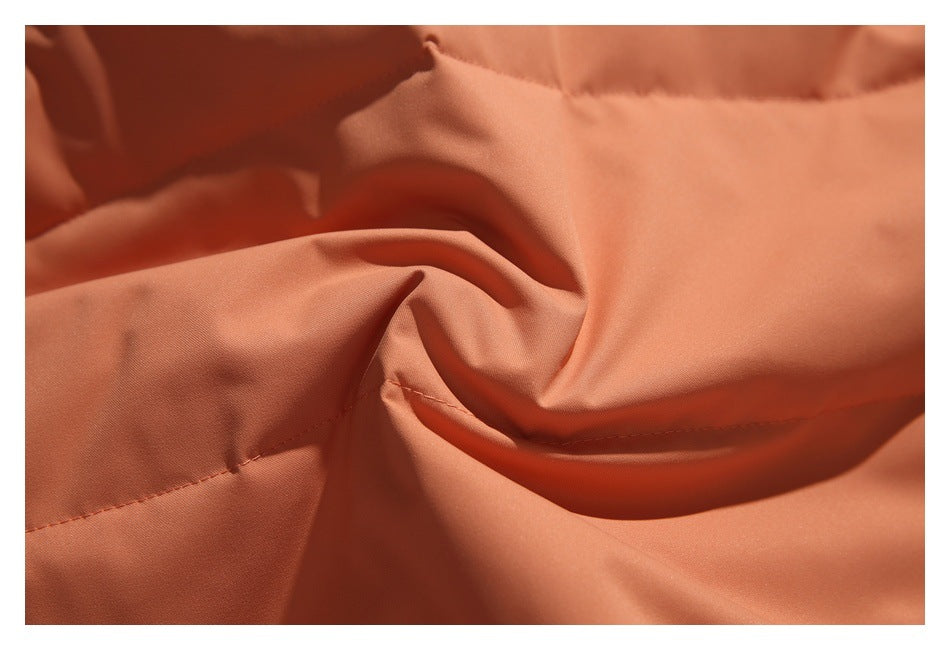Close-up of orange fabric draped in folds, with a stitched seam visible.