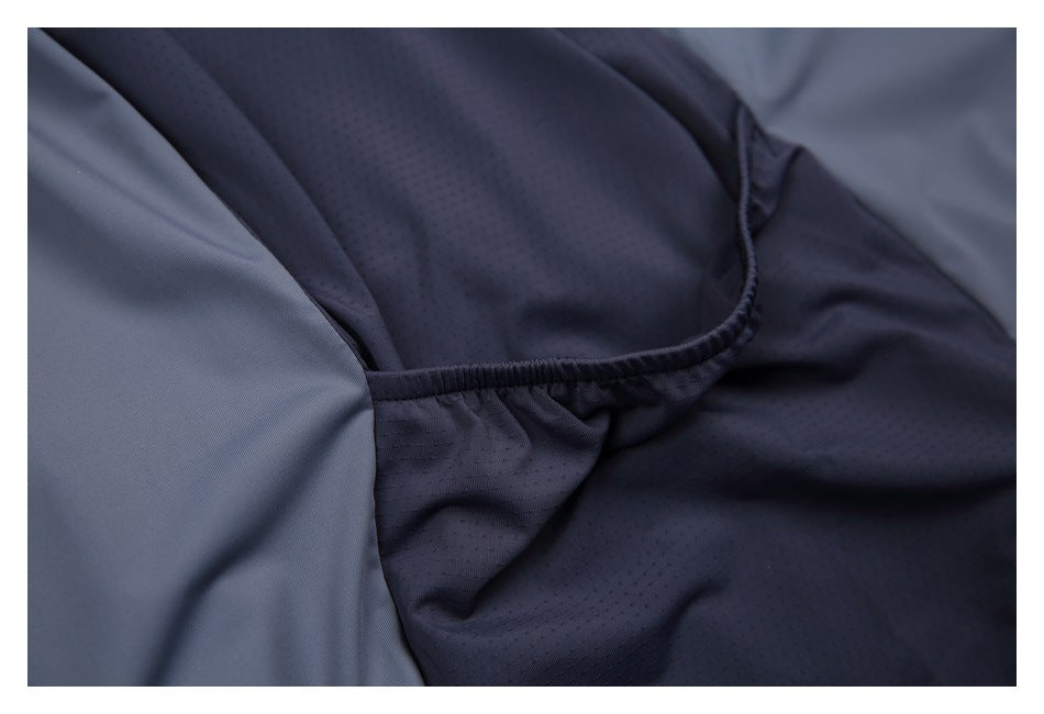 Close-up of dark navy perforated fabric gathered and stitched along a seam beside a smooth gray panel.