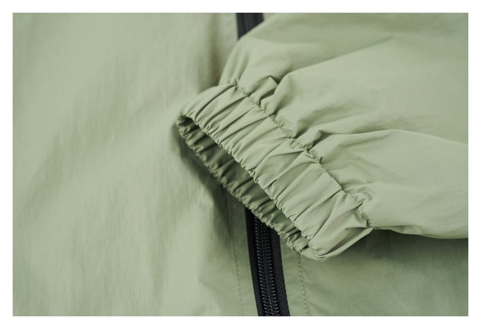 Close-up of the sage green jacket’s gathered elastic sleeve cuff beside the black front zipper.