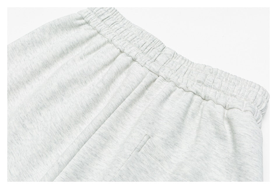 Close-up of light gray marl sweatpants showing the gathered elastic waistband and a seam.