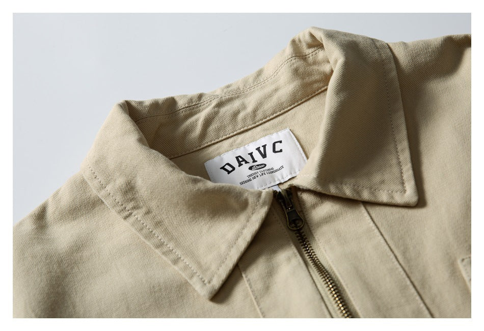 Close-up of the beige jacket's collar and brass zipper, with a sewn neck label.