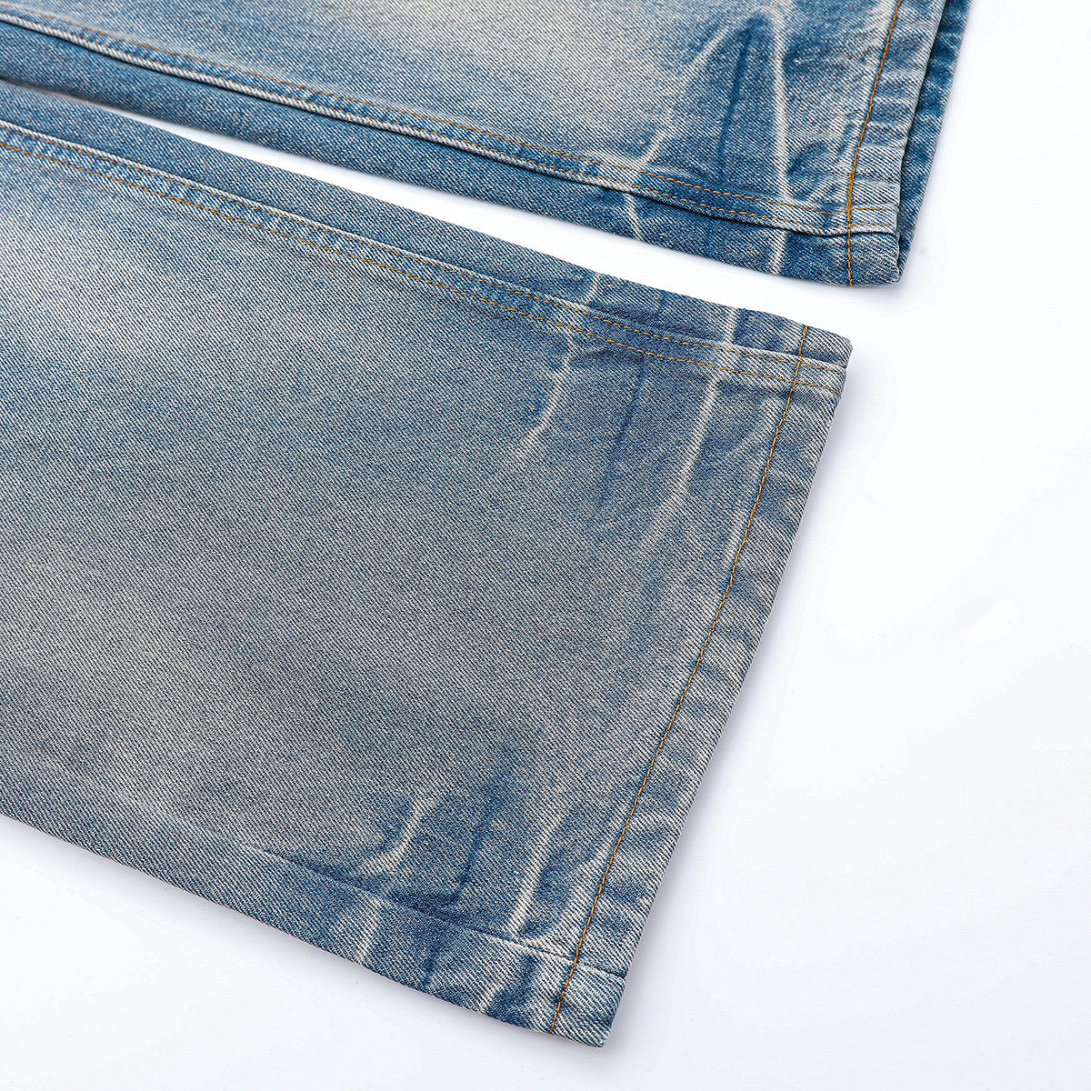 Close-up of the faded light blue jeans showing the stitched hems and leg seams.