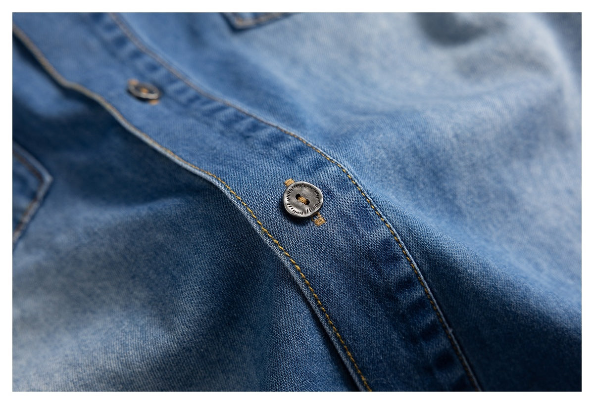 Close-up of a blue denim shirt placket with a metal button and tan stitching.