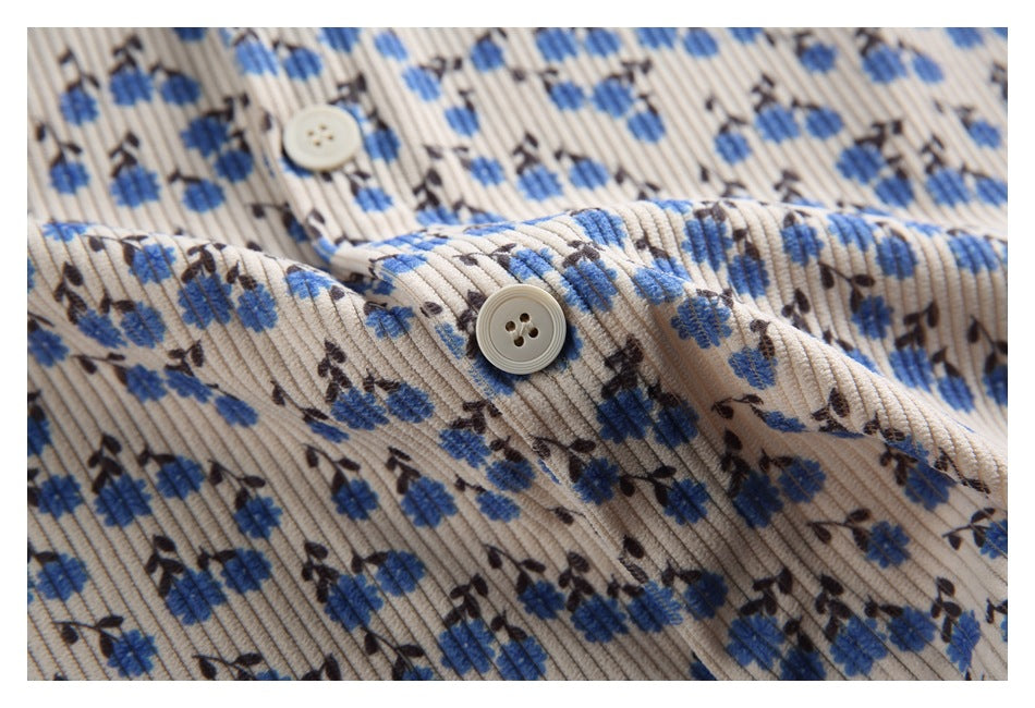 Close-up of a cream button and ribbed blue floral fabric on the shirt.