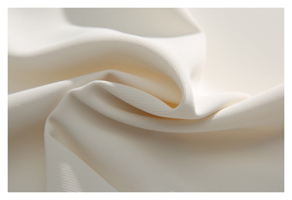Close-up of ivory fabric draped in soft folds, showing a fine ribbed texture.