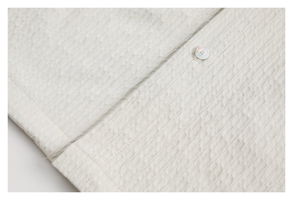 Close-up of ivory textured fabric showing a button and overlapping placket.